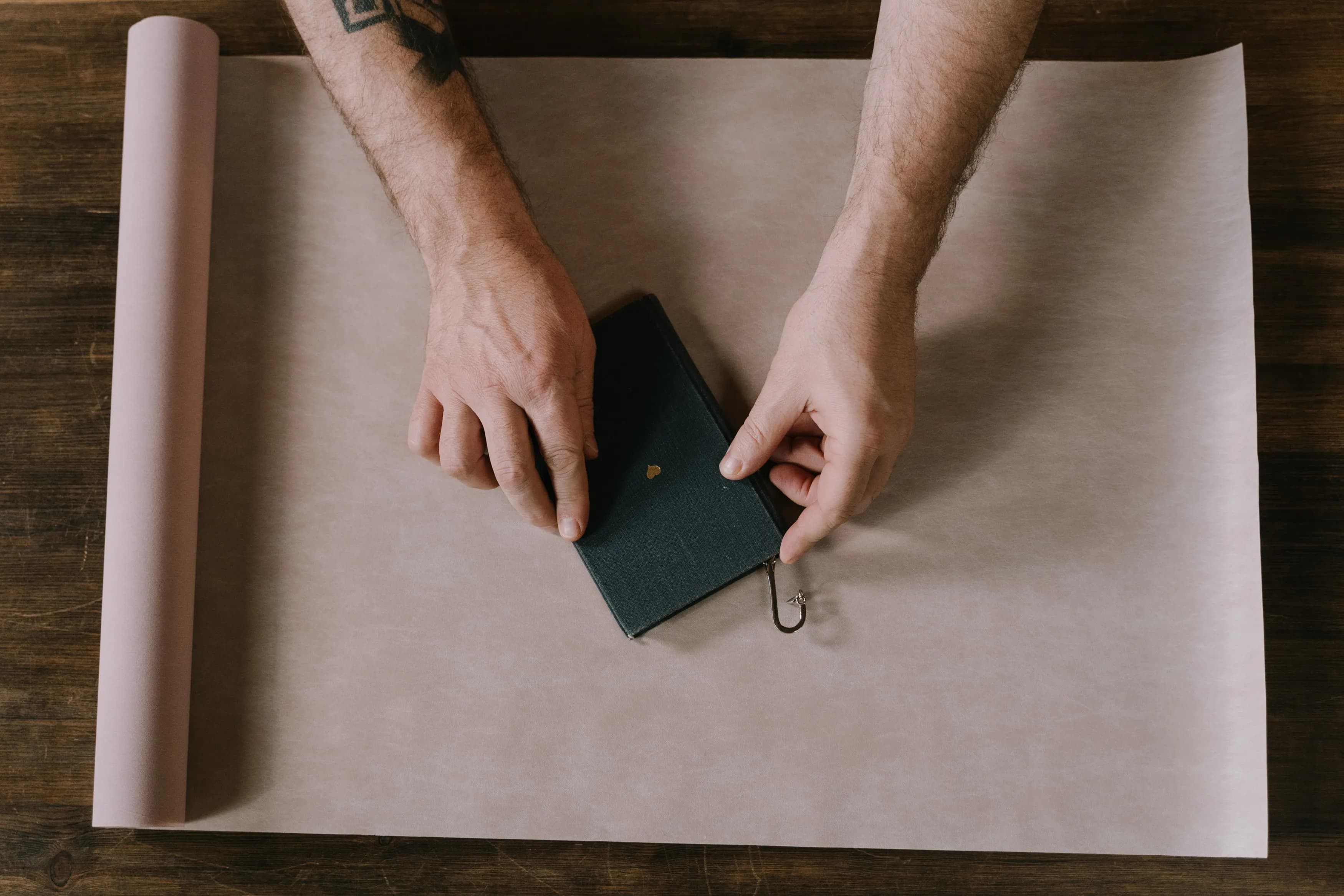 Hands wrapping a book in kraft paper